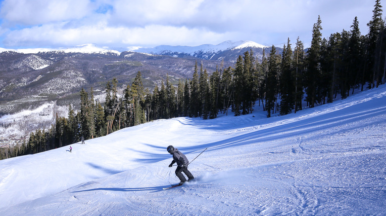 A man in a grey ski jacket downhill skiing on an alpine trail in the Colorado Rocky Mountains