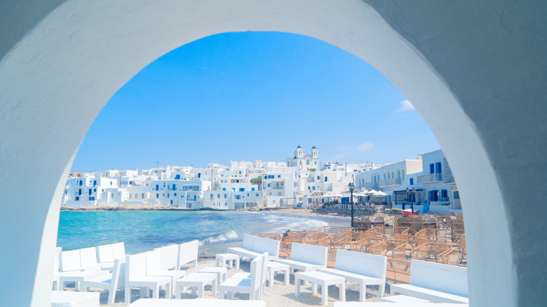 Naoussa town waterfront harbor in Paros, with white buildings and white tables and benches