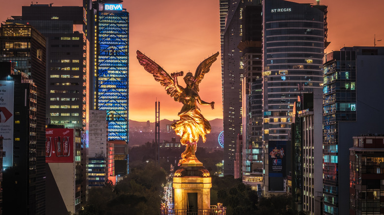 Mexico City's Angel of Independence monument at night, surrounded by buildings