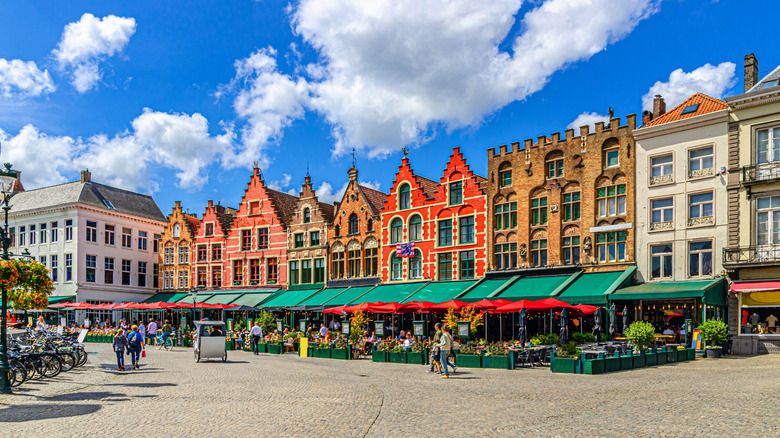 Traditional Flemish-Baroque-style townhouses with colorful facades and terrace restaurants on Markt square in Bruges, Belgium