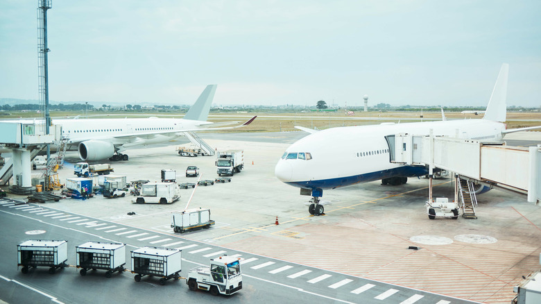 Two airplanes on the tarmac at an airport on an overcast day.