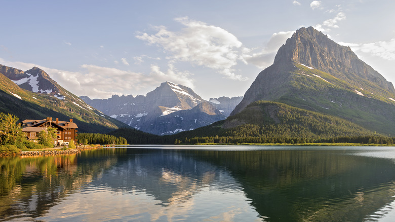 A brown building with mountains and sky reflecting onto a lake