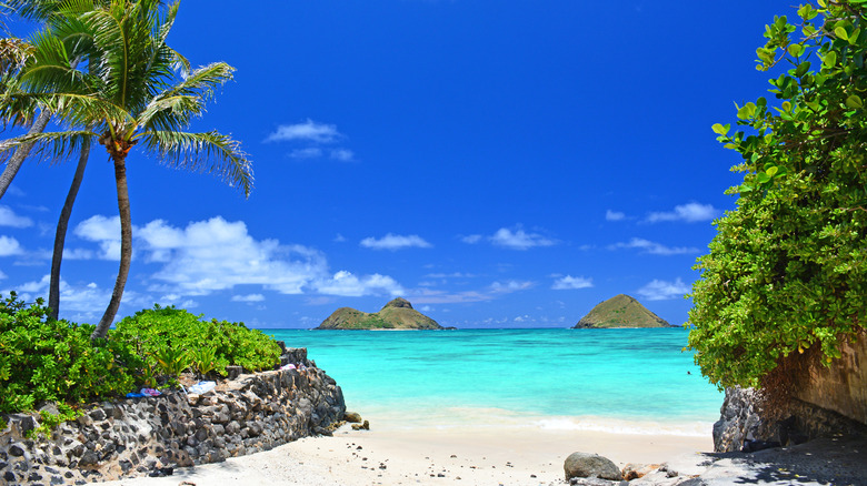 Hidden beach with view of the Mokes and turquoise waters on a clear sunny day at Lanikai Beach, Oahu, Hawaii