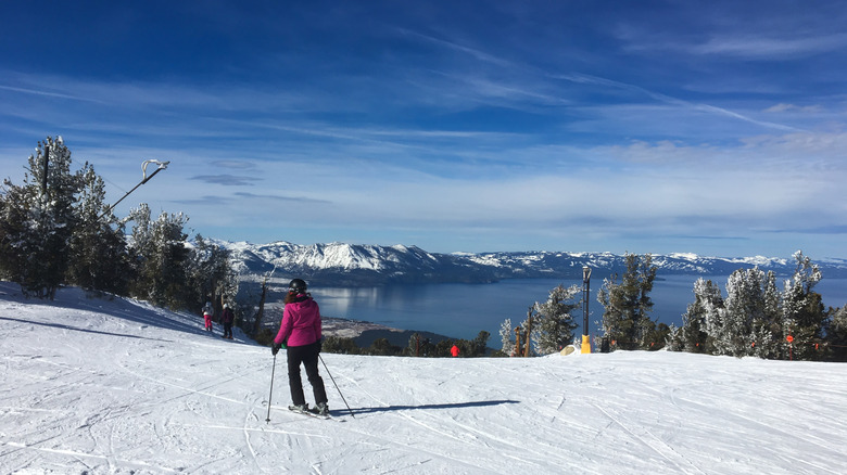 Woman skiing down a slope, enjoying winter sport activity with mountain lake view in South Lake Tahoe.