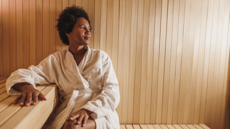 A woman wearing a bathrobe relaxing in a sauna
