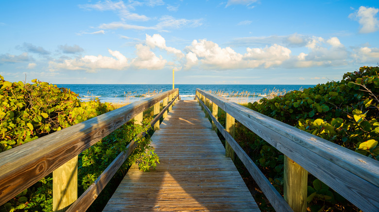 Boardwalk on beautiful Cocoa Beach, Florida, with a blue sky and clouds.