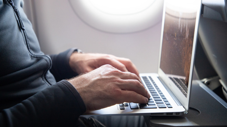 Someone using a laptop on a plane