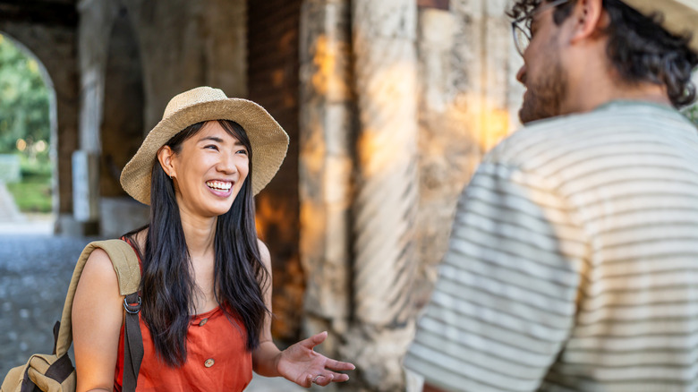 A smiling woman and a man talking near a bridge