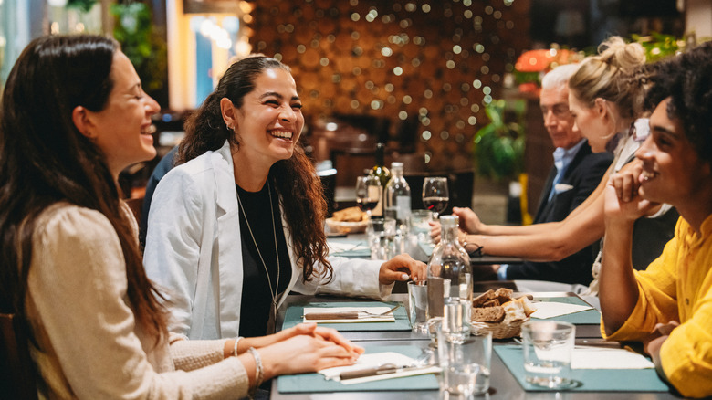 Group of friends laughing and enjoying dinner together at a restaurant