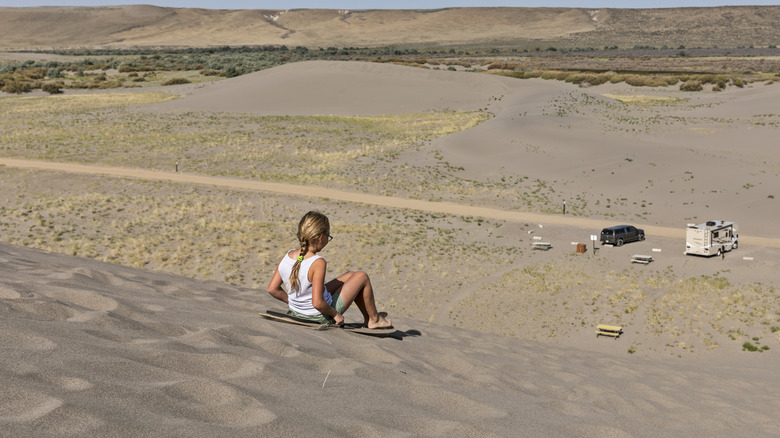A girl sandboarding at Bruneau Dunes State Park
