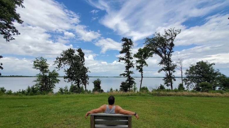 A man looking out at the lake from a bench inside Three Rivers State Park