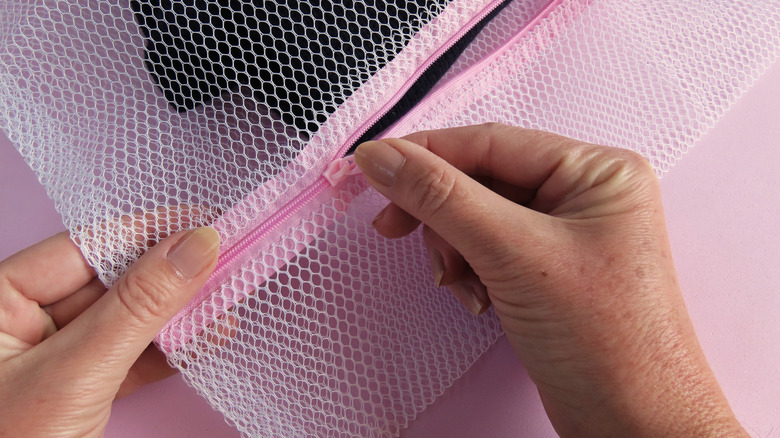 A close-up of someone zipping a mesh laundry bag
