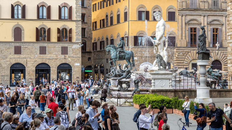 Tourists crowd around the Fountain of Neptune in Piazza Navona in Rome, Italy.
