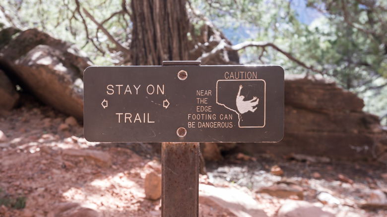 Stay On Trail Warning Sign on cliffside trail.