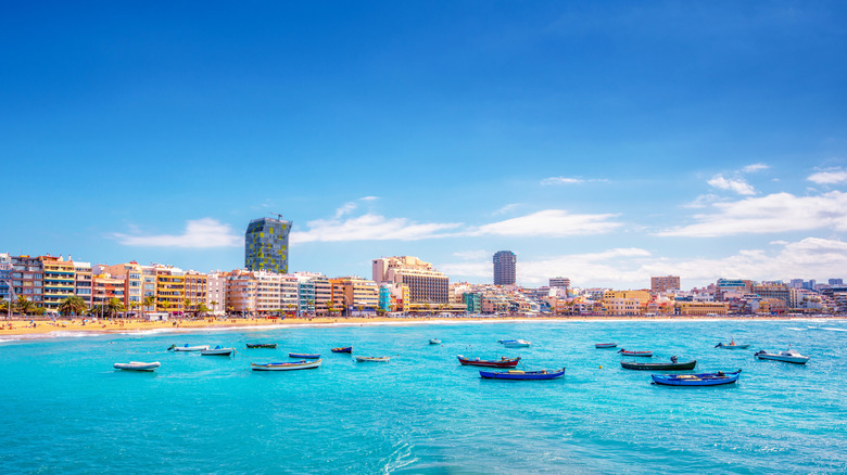 Boats in the water of Tenerife, Canary Islands, with busy shoreline and buildings in background.