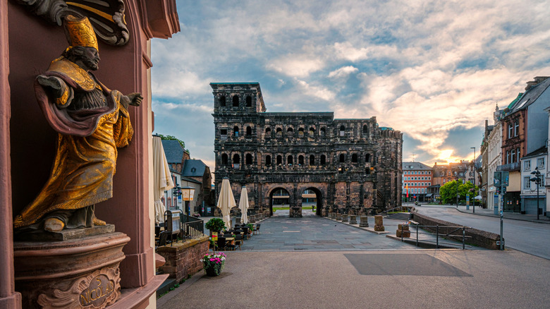 Trier's famous Roman gate, Porta Nigra, in view of a church with a gold-enrobed statue, Germany