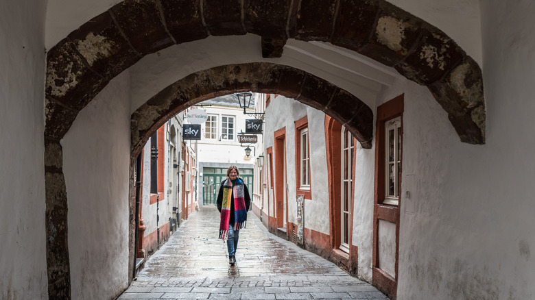 Woman walking through old gate in Trier that was once the entrance to its Judengasse, or Jews' Alley, Germany