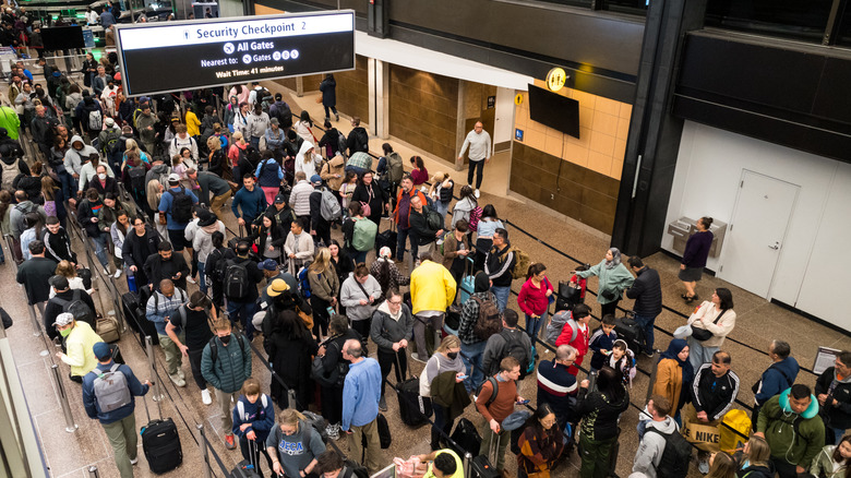 A crowd of people lined up in an airport security area