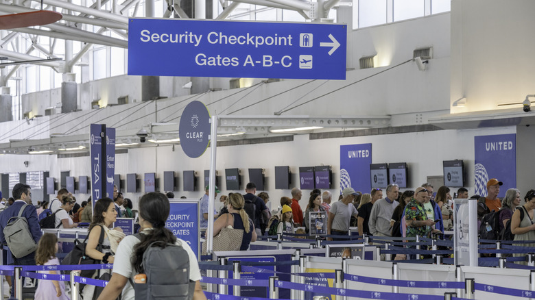 Passengers enter TSA security checkpoint at a busy airport.