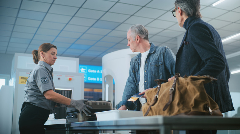 Two men preparing to pass through the security checkpoint at an airport