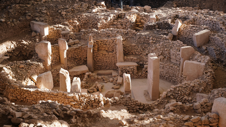 View of partially excavated section of Göbekli Tepe temple complex in Turkey with visitor walkway above the ruins