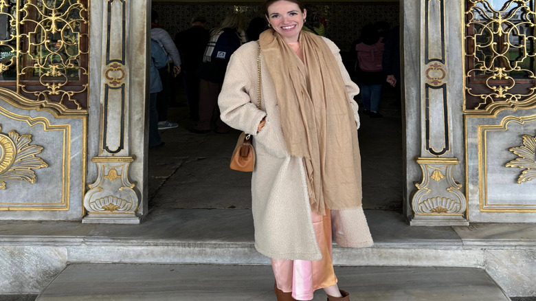 Brunette woman in a tan scarf an jacket standing in a doorway at Topkapi Palace