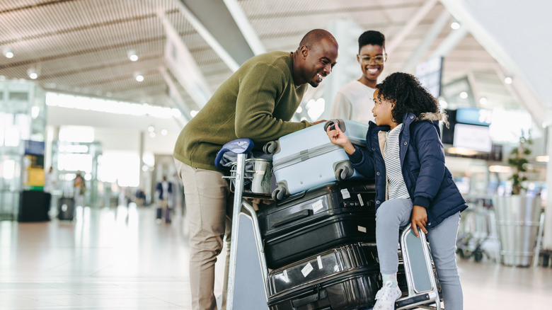 Parents and a kid at an airport with luggage