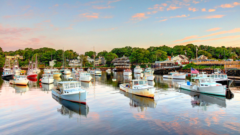 Boats float in the harbor with pink clouds reflected in the water in Ogunquit, Maine
