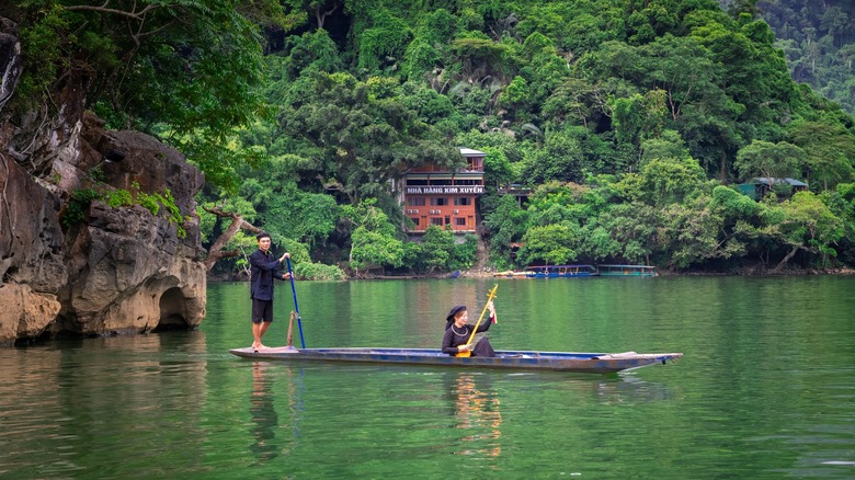 A Tay man and woman on a narrow boat in Ba Be Lake
