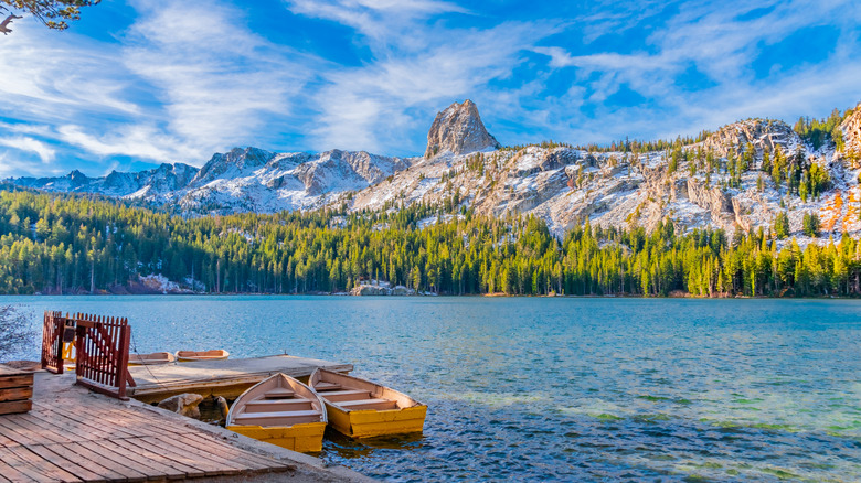 Two row boats sit at a dock on a lake with mountain in background