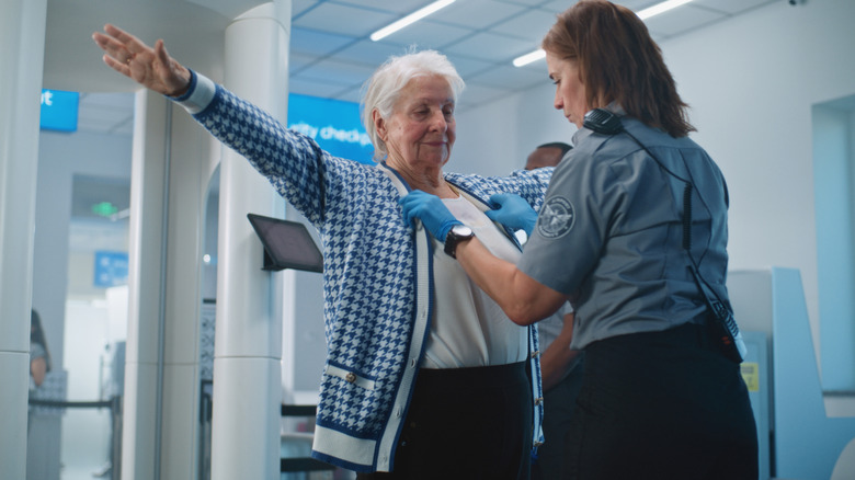 Airport security inspecting an elderly passenger