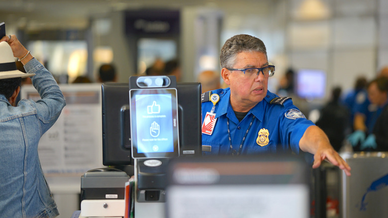 A TSA officer motioning to a traveler