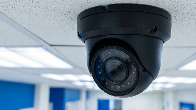 A black security camera attached to a ceiling