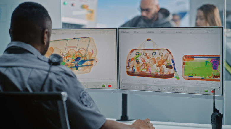 A security officer at a computer screen that shows an X-ray of luggage