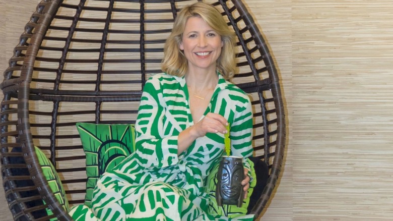 Samantha Brown sitting in a wicker chair enjoying a drink.
