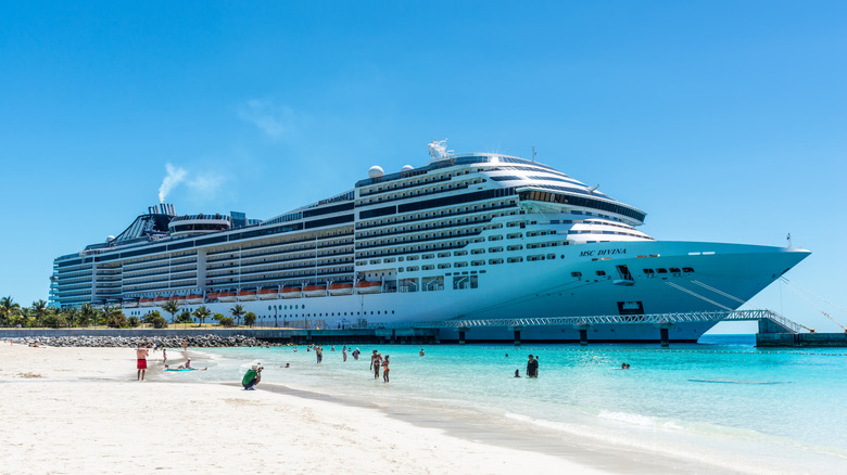 A large cruise ship docked next to a beach in the Bahamas.