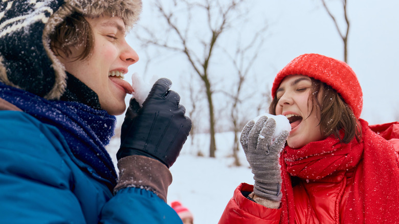 Young couple laughing while tasting snow.