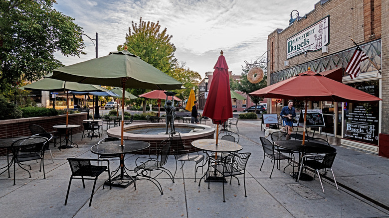 Outdoor tables and chairs under umbrellas near a bagel shop in Grand Junction