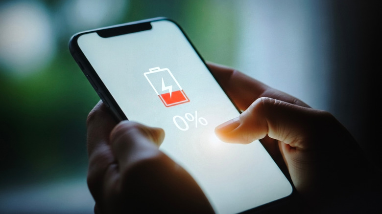 A smartphone screen shows a 0% battery charge.