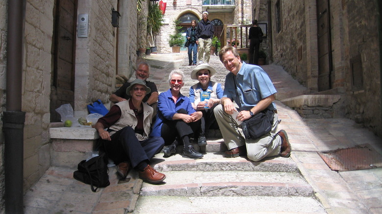 Group of tourists pose with Rick Steves on the steps of a European city