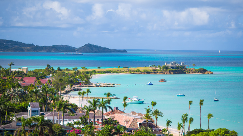 Aerial view of Caribbean island with beachside resorts, palm trees, and boats in the water.