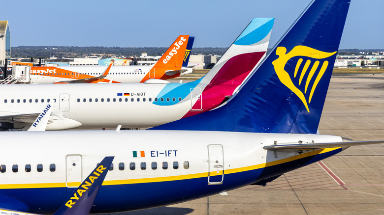 Exterior of airport terminal showing several European planes on clear summer day.