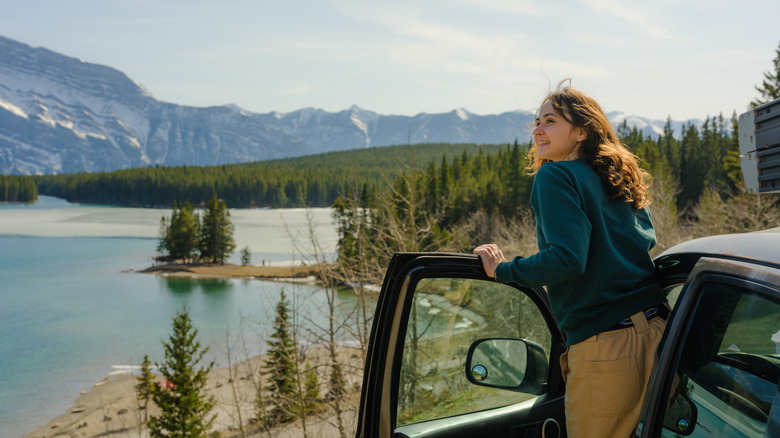 A woman looking at a lake view along the road in her car