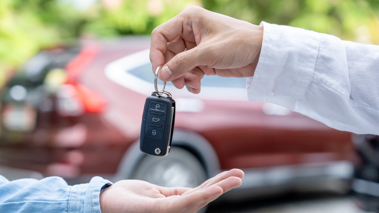 A person handing a car key to another person