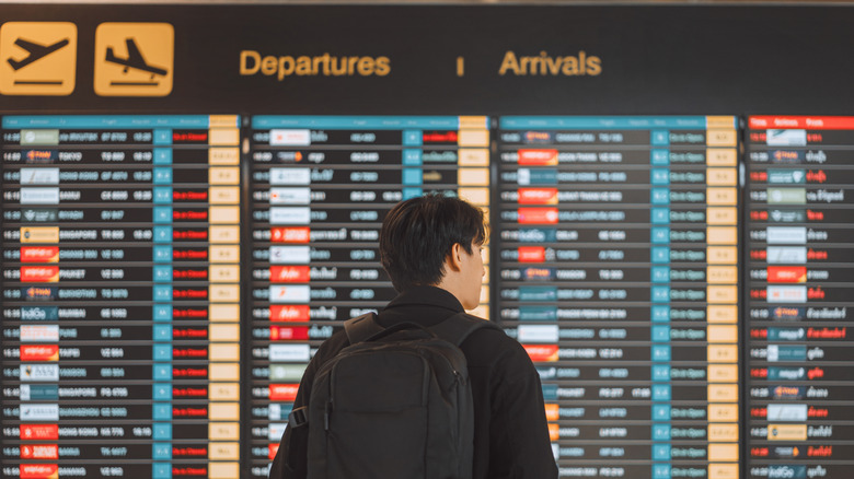 back view of man with backpack checking flight information
