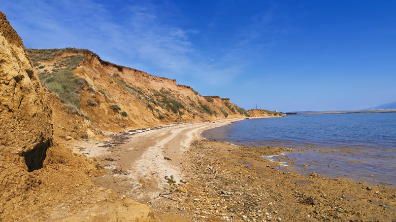 a steep cliff to the left ovrlooking sandy beach to the right