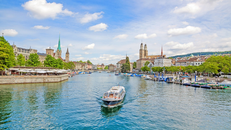 Tourist boat cruising down the center of Zurich's Limmat River through the Old Town