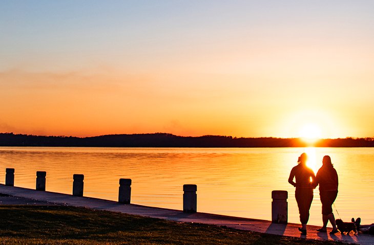Couple walking on a path along Lake Monona at sunset