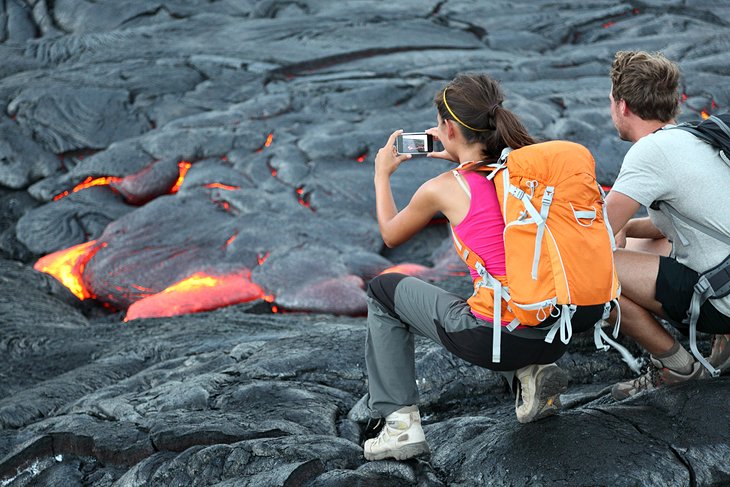Touristes photographiant de la lave chaude dans le parc national des volcans d'Hawaï