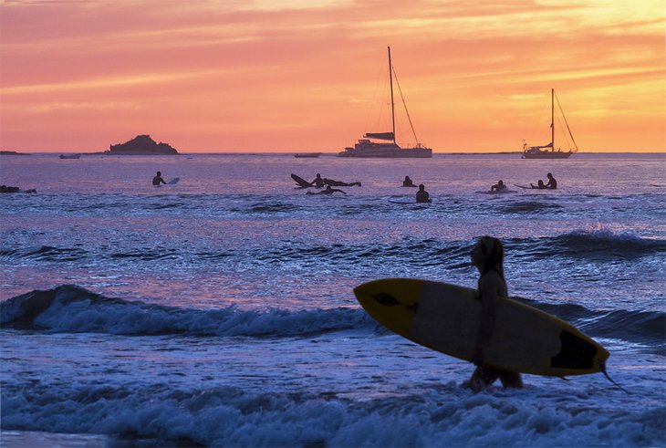 Surfeurs se découpant au coucher du soleil sur la plage de Tamarindo